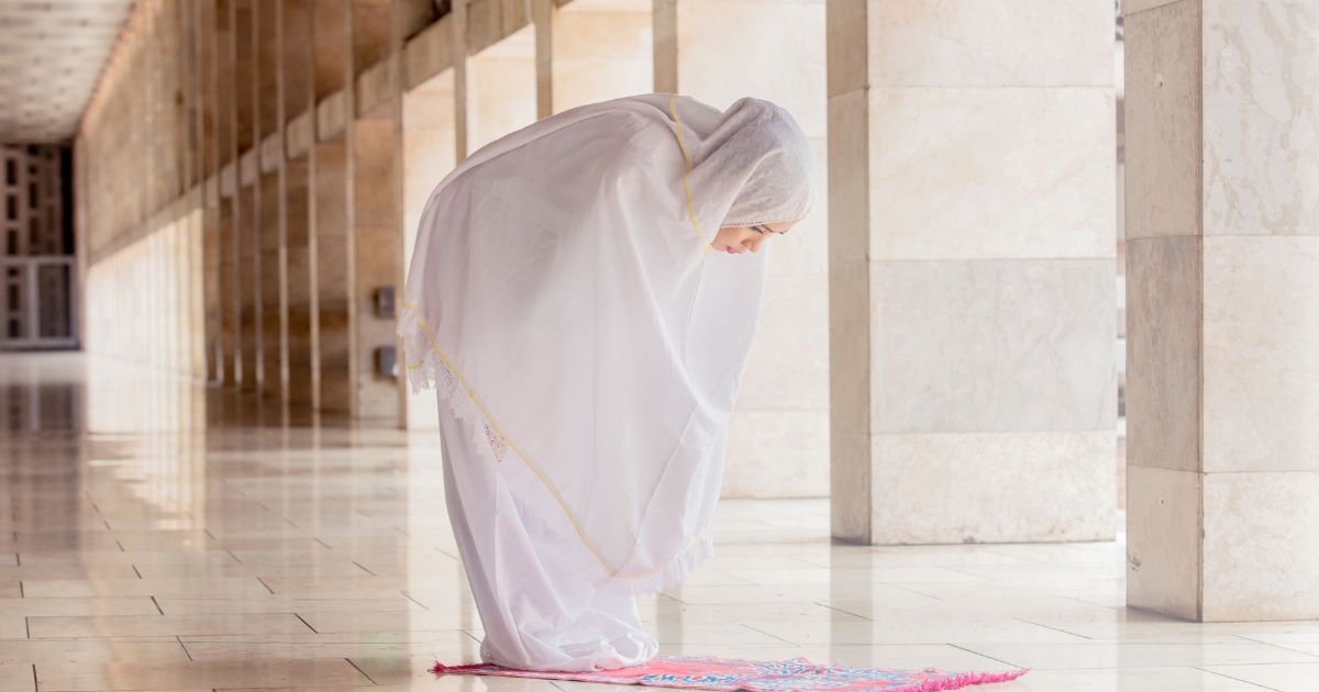 Seorang wanita muslimah sedang melaksanakan sholat di pelataran masjid