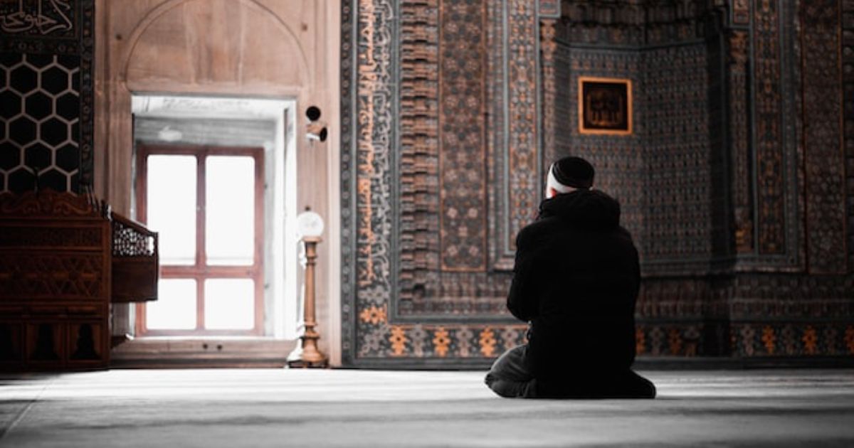 A muslim man performing prayer in sitting position in the mosque