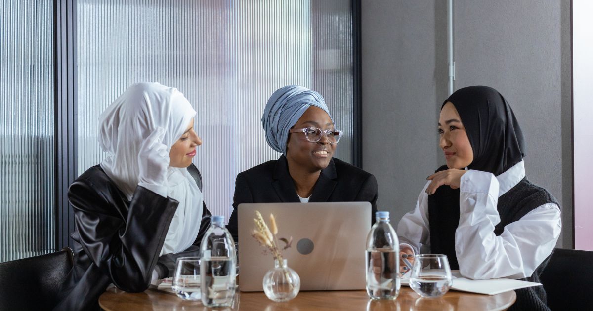 A group of Muslim women are gathered together, smiling and looking happy