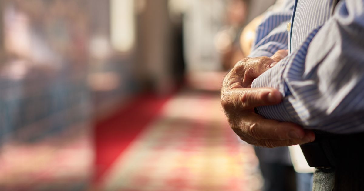 Muslim men praying in a straight row to shorten the Islamic daily prayers