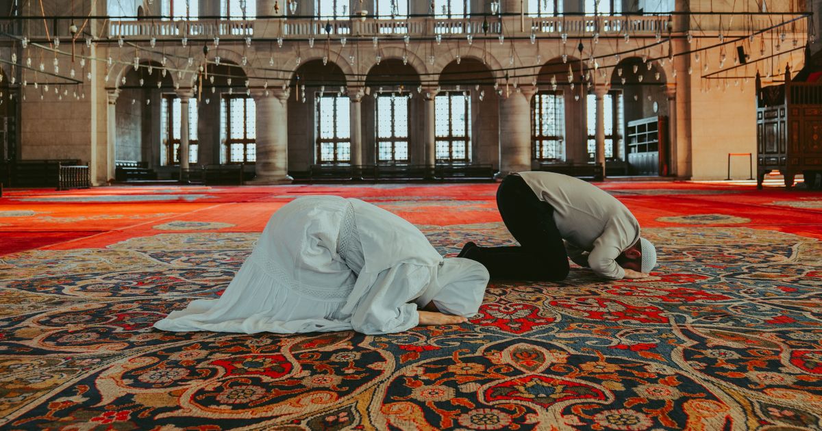 A Muslim man and woman are praying together in the congregation.